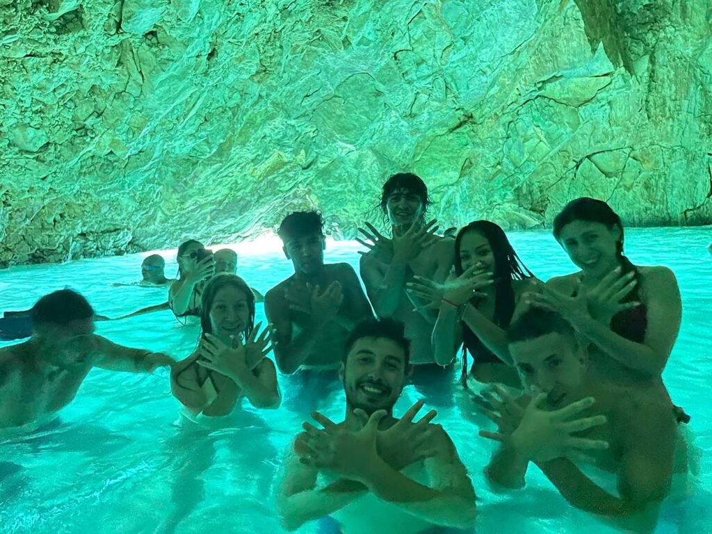 Group of friends posing inside the Hidden Blue Cave in Vlore, Albania, enjoying the glowing turquoise waters and unique cave lighting."